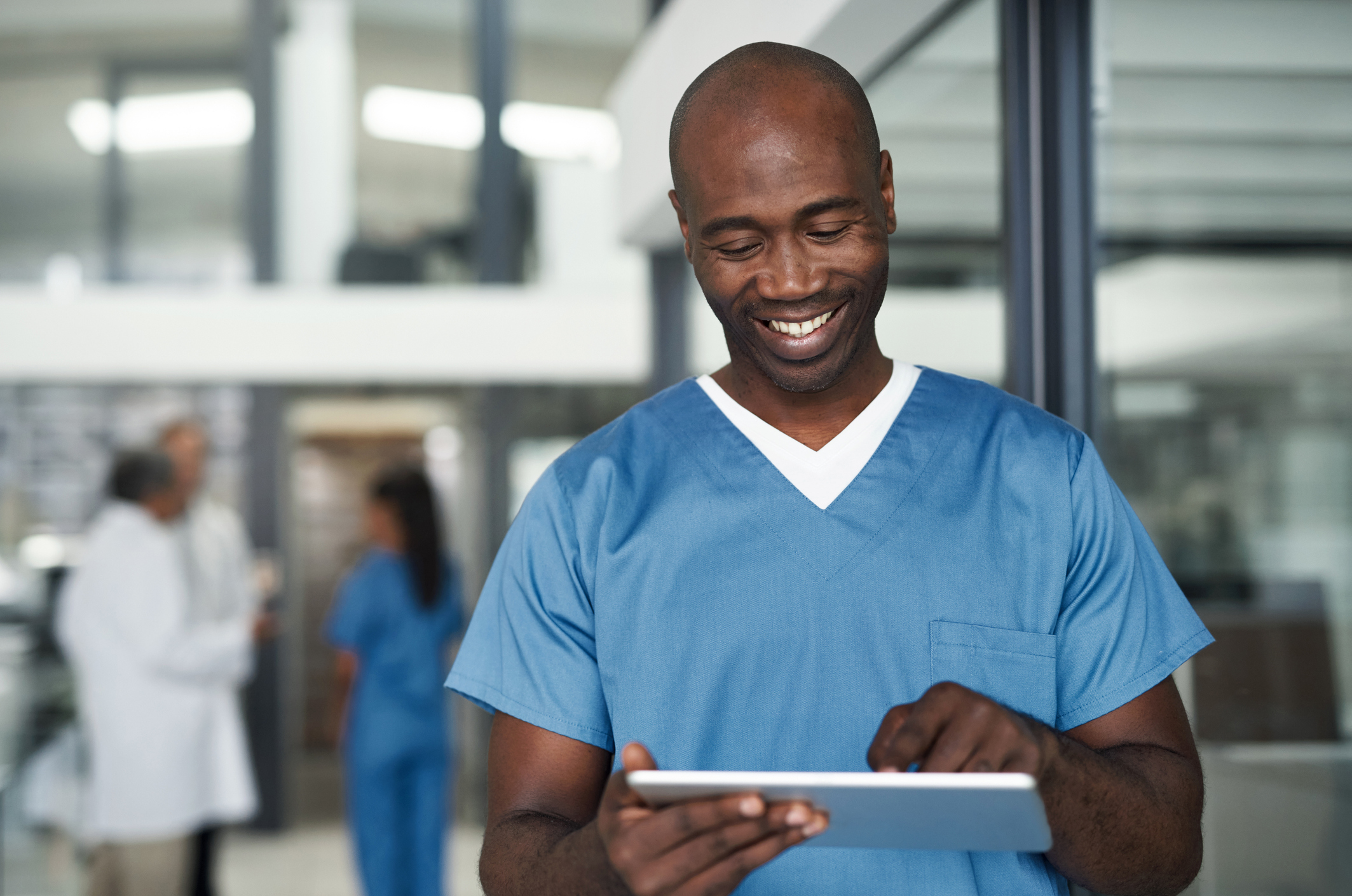 Male nurse looking down at nursing procedures on tablet